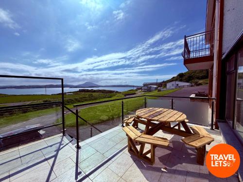 un tavolo da picnic in legno su un balcone con vista sull'oceano di Atlantic View Retreat a Downings