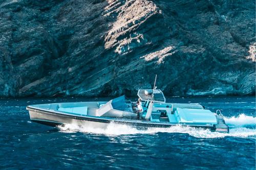 un bateau bleu dans l'eau près d'une montagne dans l'établissement Santorini Private Tour - Sunny Zeus, à Santorini