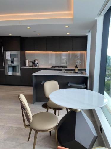 a kitchen with a table and chairs and a counter at Brand New Modern 2 BR Condo in Heart of Downtown Vancouver in Vancouver