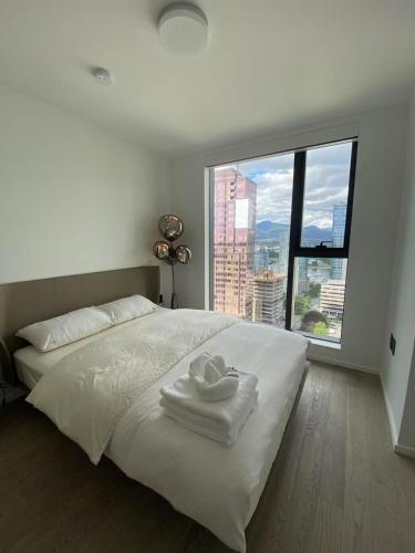 a white bed with two towels and a large window at Brand New Modern 2 BR Condo in Heart of Downtown Vancouver in Vancouver