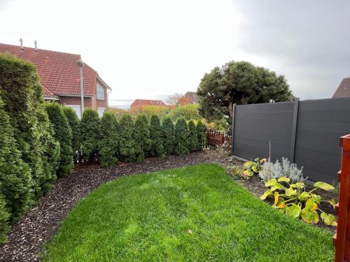 a garden with green grass and a fence at ruhig gelegenes Ferienhaus mit Kamin in Dornum