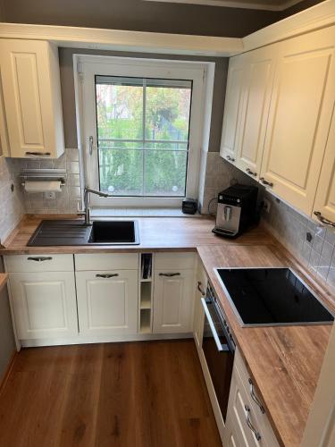 a small kitchen with white cabinets and a window at ruhig gelegenes Ferienhaus mit Kamin in Dornum