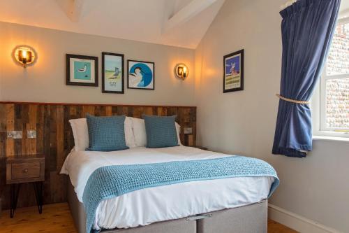 a bedroom with a bed with blue and white sheets at The Three Swallows Cley in Cley next the Sea