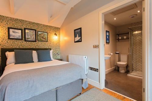 a bedroom with a bed and a bathroom with a toilet at The Three Swallows Cley in Cley next the Sea