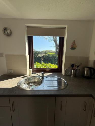 a kitchen counter with a sink in front of a window at Cosy cottage between Penzance and St Ives in Gulval