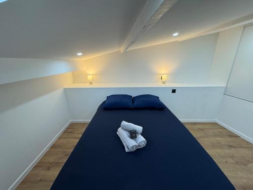 a bedroom with a blue bed with towels on it at La lyonnaise dans la jungle urbaine in Vénissieux