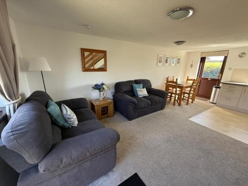 a living room with two couches and a kitchen at Cosy cottage between Penzance and St Ives in Gulval
