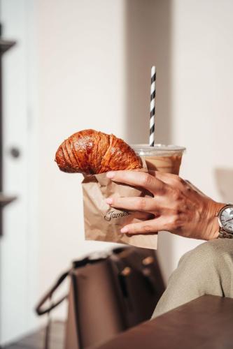 a woman holding a cup of coffee and a pastry at Pietermaai Oasis in Willemstad