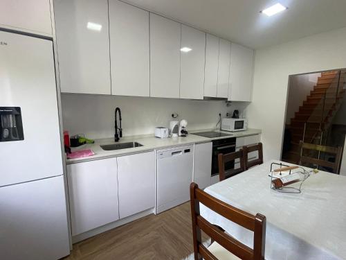 a kitchen with white cabinets and a white table with a tableablish at Miranda Village House in Miranda do Corvo