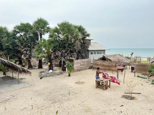 un hombre sentado en una mesa en una playa en Delft Jeyam Resorts, en Delft East