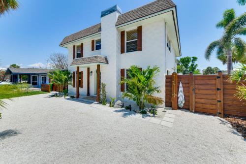 a white house with a fence and palm trees at Walk to Gulf Luxe Luau-Themed Gem in Holmes Beach in Holmes Beach