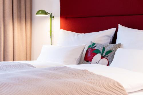 a bed with white sheets and pillows with a red headboard at Apfelland Hideaways mit Sauna in Puch bei Weiz
