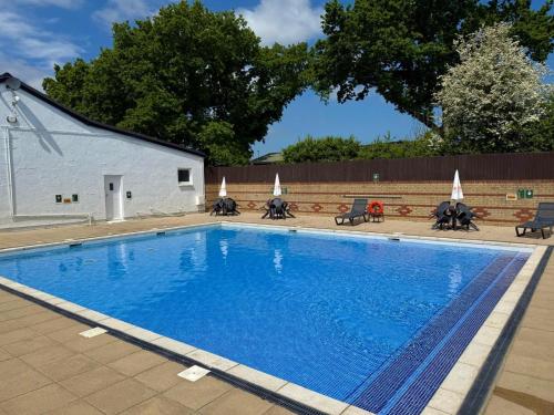 a large blue swimming pool next to a building at Red Squirrel Lodge in Sandown