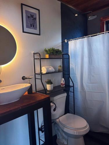 a bathroom with a white toilet and a sink at Cabaña Las Brumas del Jaular in Tapantí