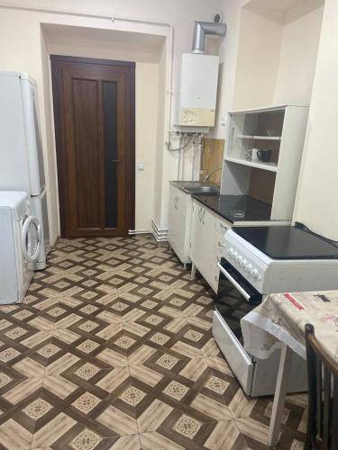una cucina con pavimento piastrellato, piano cottura e frigorifero di Дом в центре a Gyumri