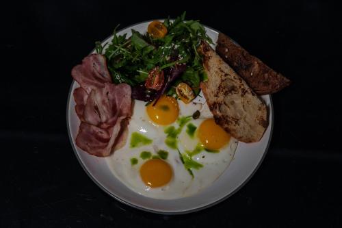 a plate of eggs and bacon and toast on a table at Arkadia Beach Hotel in Odesa