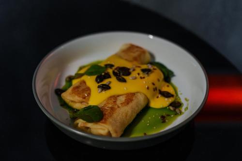 a white bowl of food with cheese and greens at Arkadia Beach Hotel in Odesa