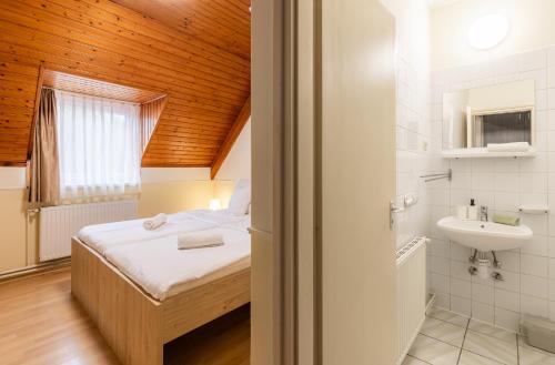 a small bedroom with a bed and a sink at Heu Réka Vendégház in Dunasziget