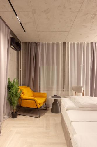 a bedroom with a yellow chair and a bed at Open Space in Niš