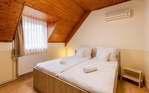 a bedroom with a large bed with a wooden ceiling at Heu Réka Vendégház in Dunasziget
