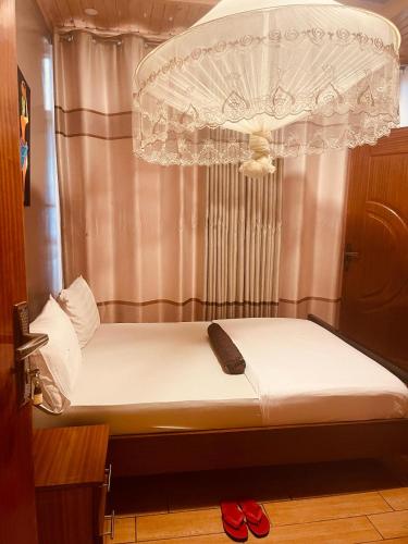a bed with a chandelier and two red shoes at ARSENE ACCOMODATION AT Kwetu&Venus KIGALI in Kigali
