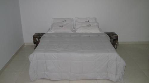 a bed with white sheets and pillows on it at Pousada Flor Dos Ipês in Trindade