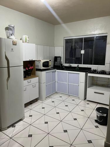 a kitchen with white appliances and a tile floor at House da Cris in Pirassununga