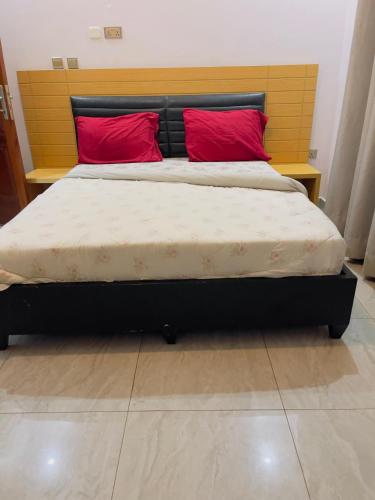 a bed with two red pillows in a bedroom at ARSENE ACCOMODATION AT Kwetu&Venus KIGALI in Kigali