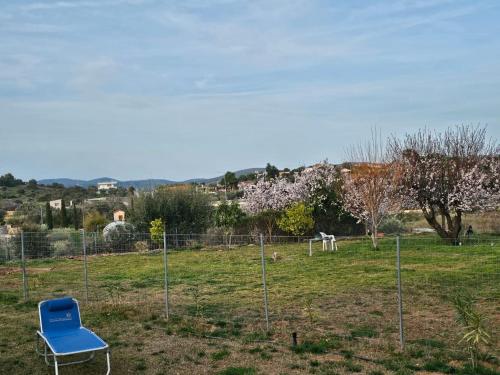 a blue chair in a field with a fence at Olive Ridge in Porto Rafti