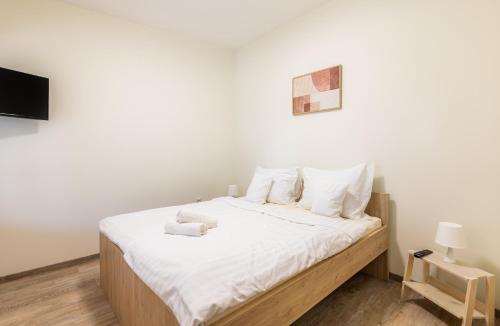 a bedroom with a bed with white sheets and a tv at Heu Réka Vendégház in Dunasziget