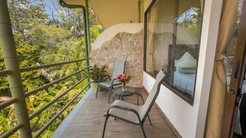 a balcony with two chairs and a table with flowers at Issimo Suites (Adults Only) in Manuel Antonio