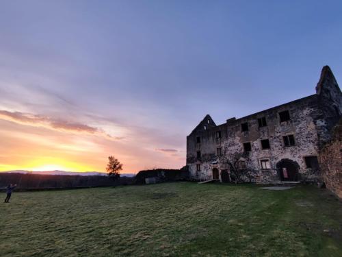 an old building in a field with the sunset in the background at Ferienwohnung Angie in Vogtsburg