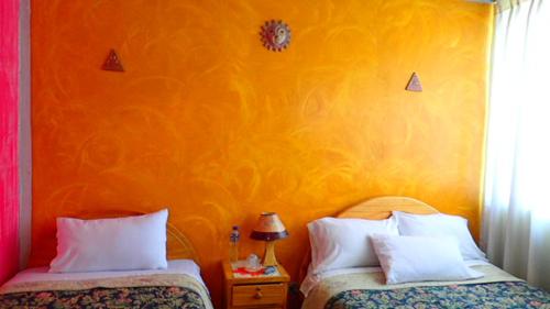 een slaapkamer met 2 bedden en een oranje muur bij OtavaloHuasi2 Quito in Quito