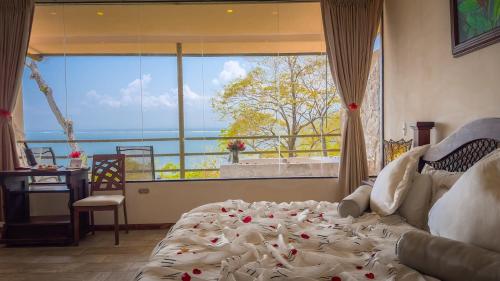a bedroom with a bed in front of a large window at Issimo Suites (Adults Only) in Manuel Antonio