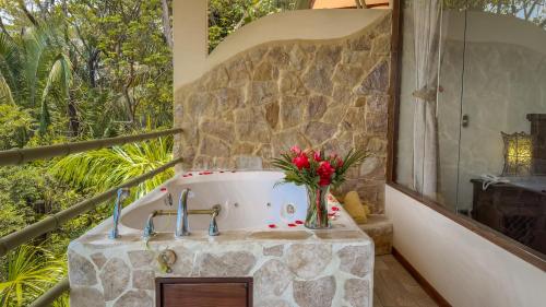 a bathroom with a bath tub with flowers in a vase at Issimo Suites (Adults Only) in Manuel Antonio
