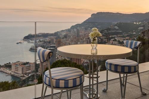 a table and chairs with a view of the city at The Maybourne Riviera, Maybourne in Roquebrune-Cap-Martin