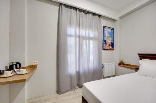 a white bedroom with a bed and a window at Regraph Hotel in Tbilisi City