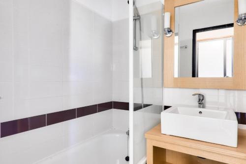 une salle de bain avec un lavabo blanc et une baignoire dans l'établissement Résidence Port du Crouesty - maeva Home - Studio bord de mer 4 personnes - Confort MAE-8813, à Arzon