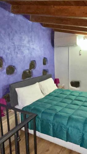 a bedroom with a bed and a purple wall at Il Rustico in Pozzillo
