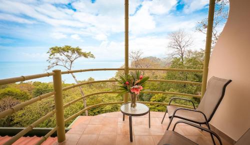 a balcony with a table and a vase of flowers at Issimo Suites (Adults Only) in Manuel Antonio