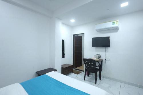 a bedroom with a bed and a desk and a tv at Hotel Season in Ahmedabad