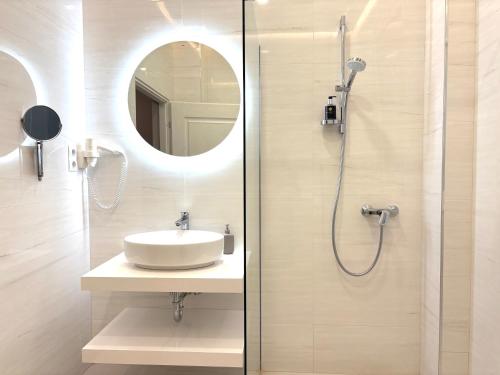 a bathroom with a sink and a shower with a mirror at Annie Villa in Siófok