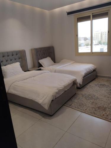 two beds in a white room with a window at اطلالة الريان شقة خاصة in Jeddah