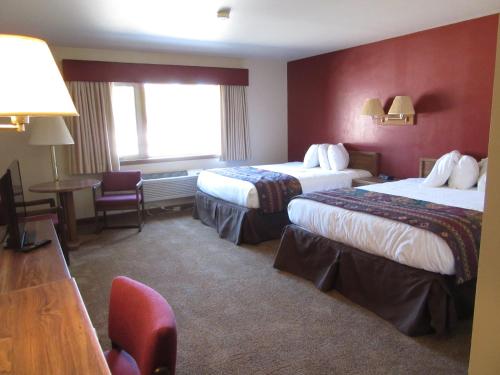 ウェスト・イエローストーンにあるアルズ ウエストワード ホ モーテルのベッド2台とテーブルが備わるホテルルームです。