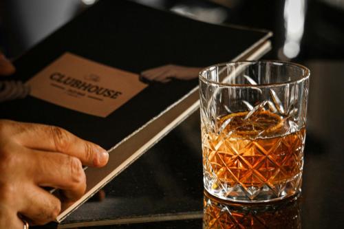 a person holding a book next to a glass of whiskey at Sheraton Ankara Hotel & Convention Center in Ankara