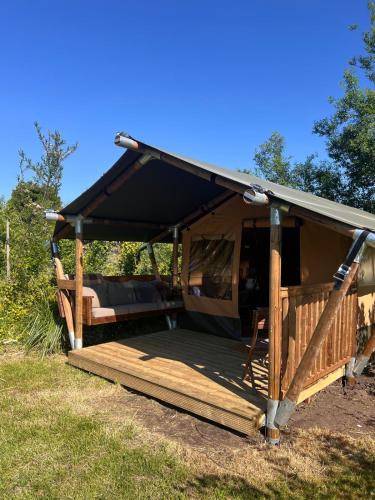 a gazebo with a black roof and a wooden deck at Een luxe safari tent in Rijsenhout