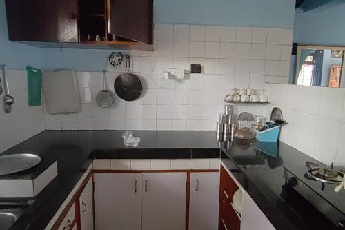 a kitchen with black counter tops and white tiles at Mati Mogra in Calangute