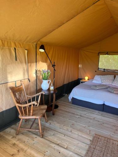 a bedroom with a bed and a chair in a tent at Een luxe safari tent in Rijsenhout