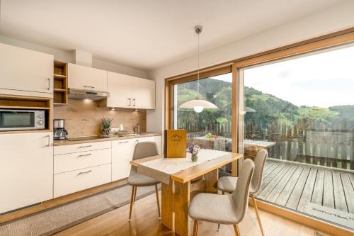 a kitchen with a table and chairs and a large window at Tratterhof Apt Eidechsspitze in Vandoies