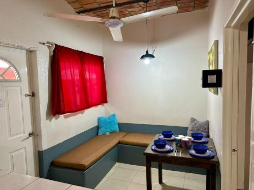 a room with a bench with a red window and a table at Bungalows Las Glorias in Rincon de Guayabitos